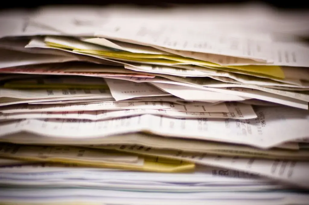 Stack of financial receipts and documents awaiting forensic review